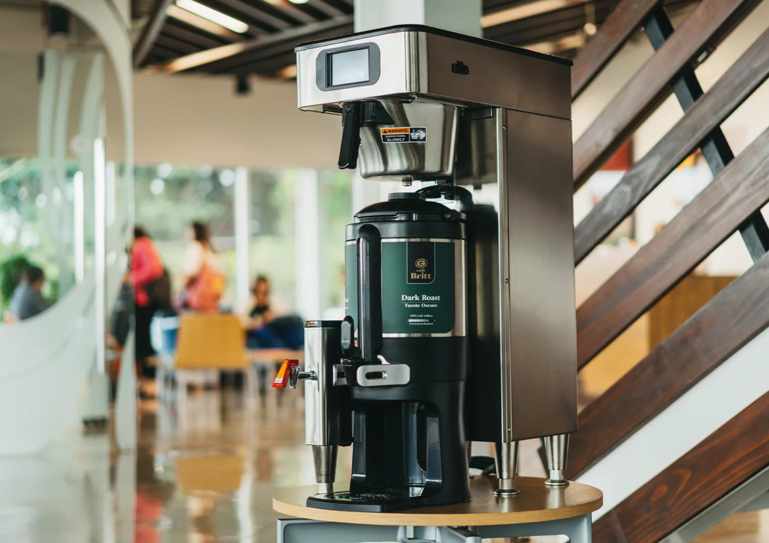 Coffee machine on a table with blurred people in the background