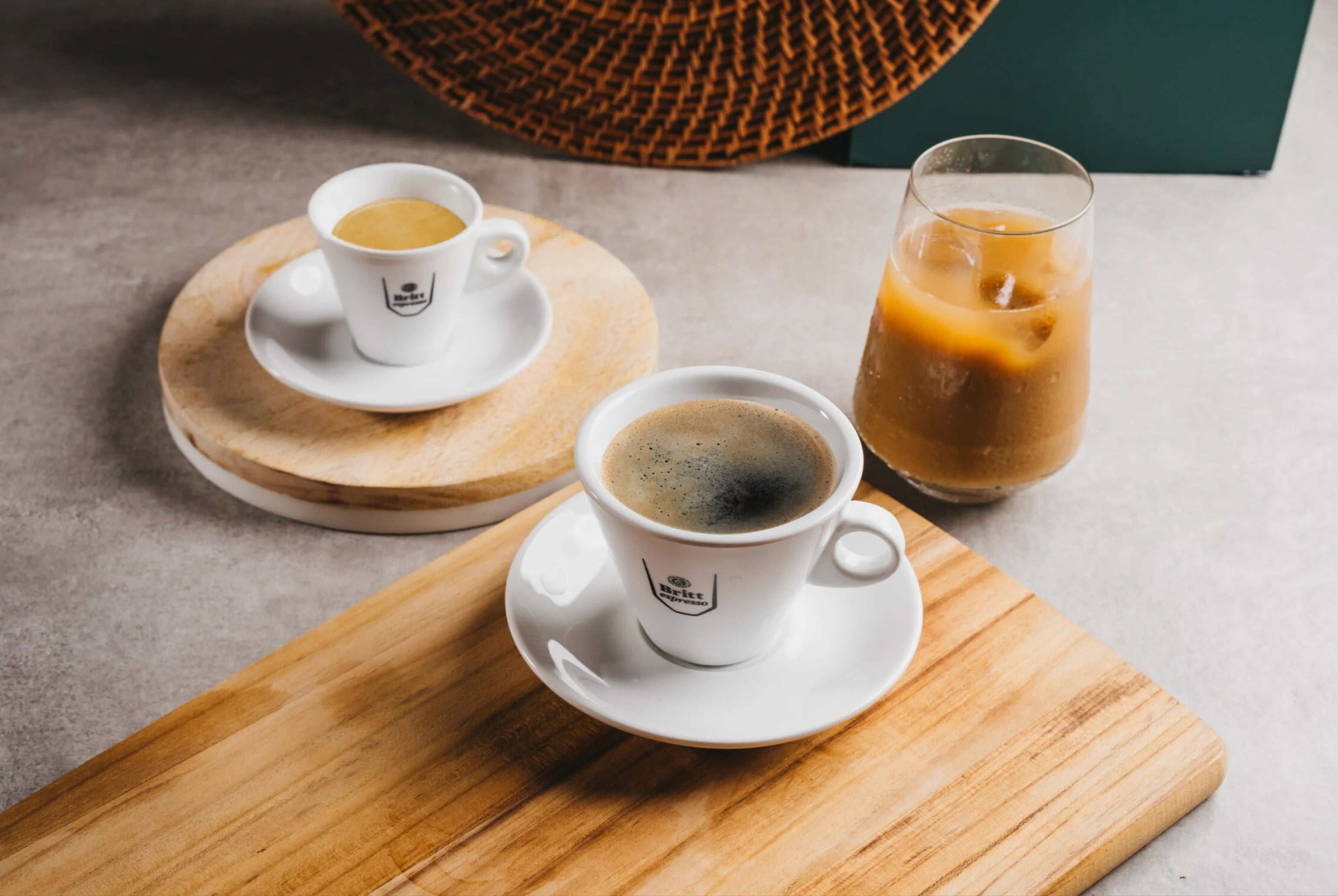 Two cups of coffee with a glass of iced coffee on a wooden board.