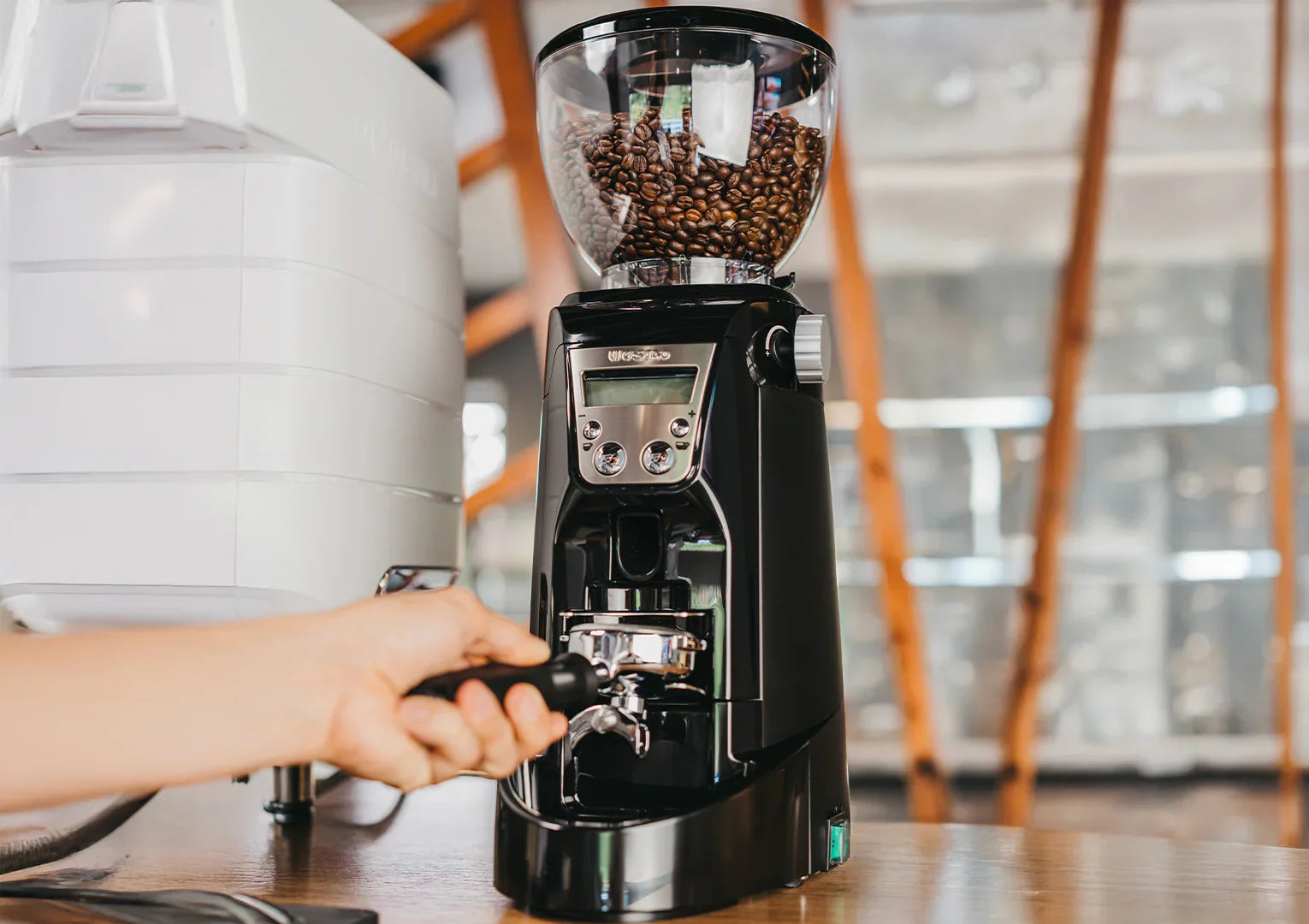 Coffee grinder with coffee beans being used on a wooden surface.