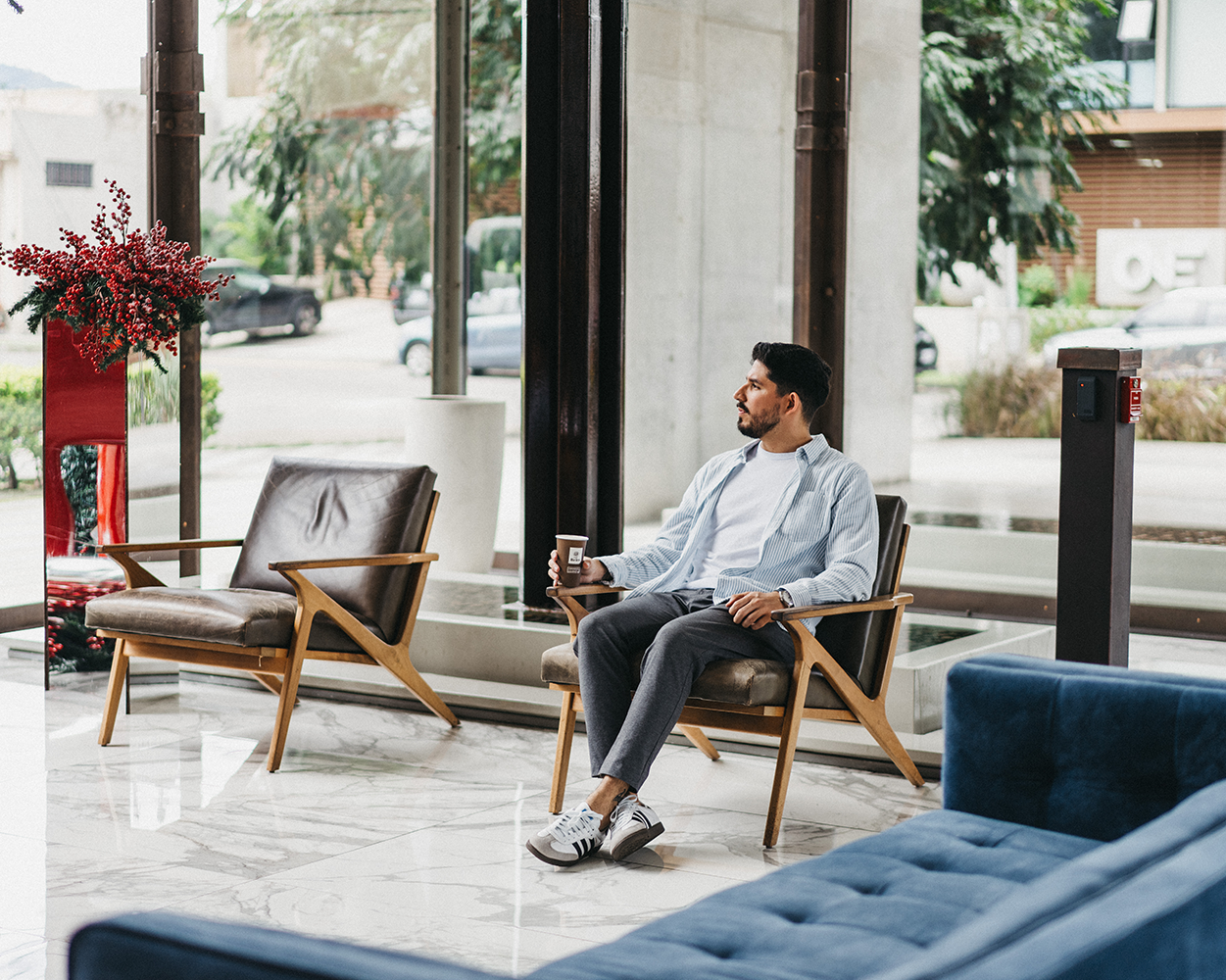 Person enjoying a cup of Café Britt gourmet Costa Rican coffee in a modern office lounge.