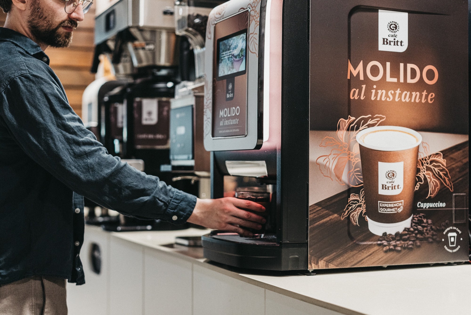 Employee using a Café Britt commercial coffee machine to prepare gourmet Costa Rican coffee.