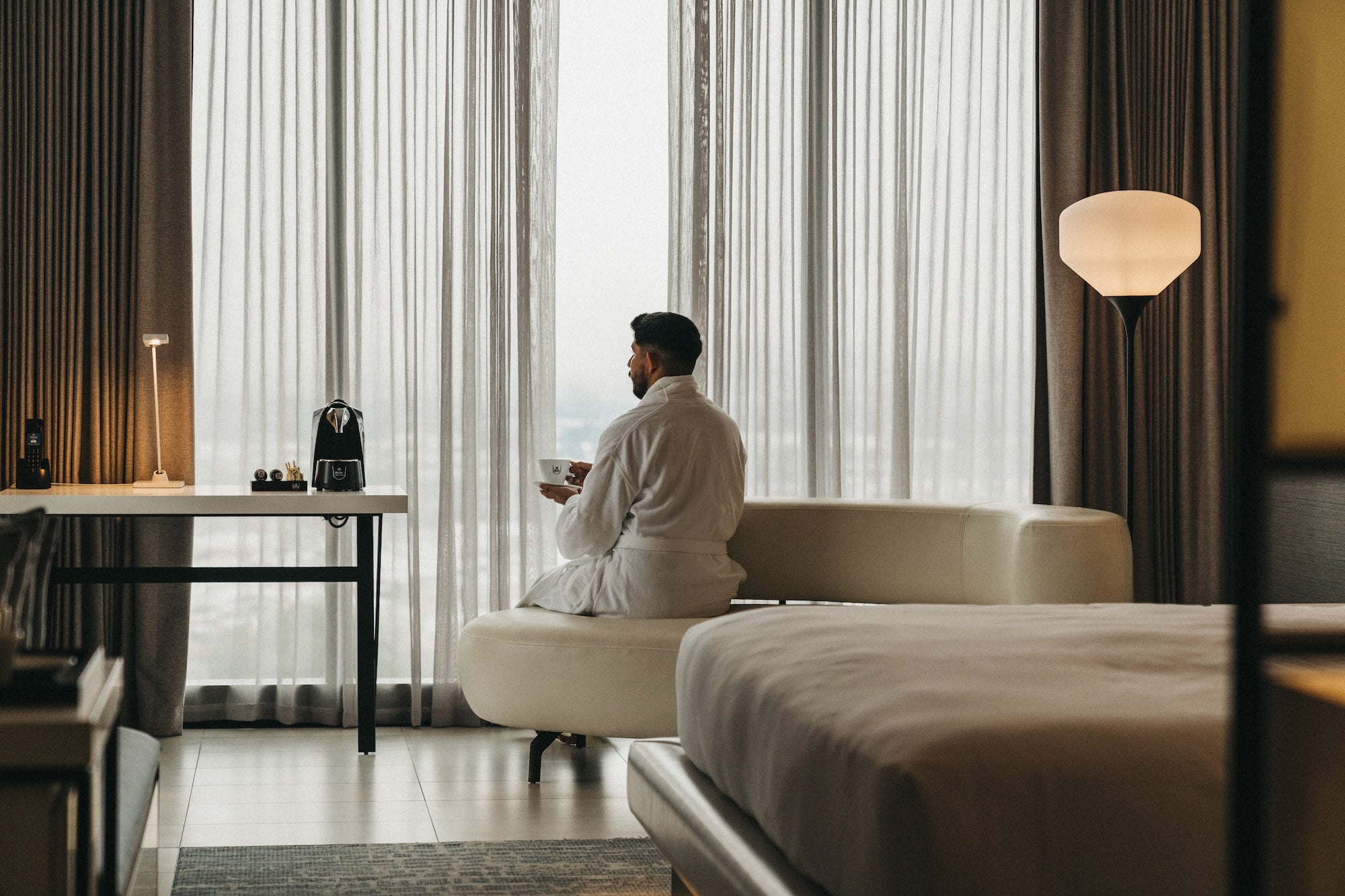 Hotel guest enjoying Café Britt coffee with an in-room coffee machine, enhancing the guest hospitality experience.
