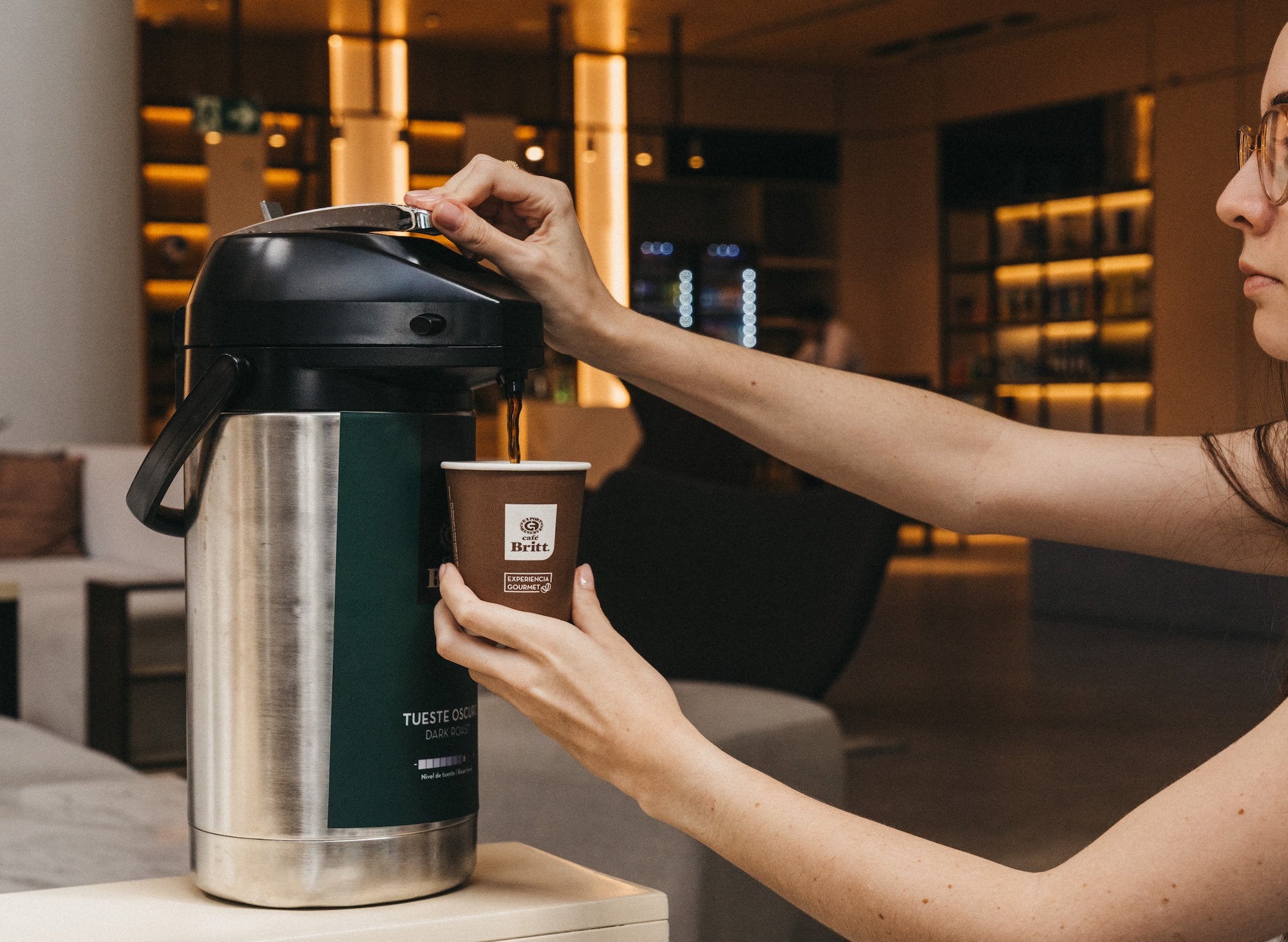 Person pouring Café Britt gourmet Costa Rican coffee into a cup in a hotel lobby.
