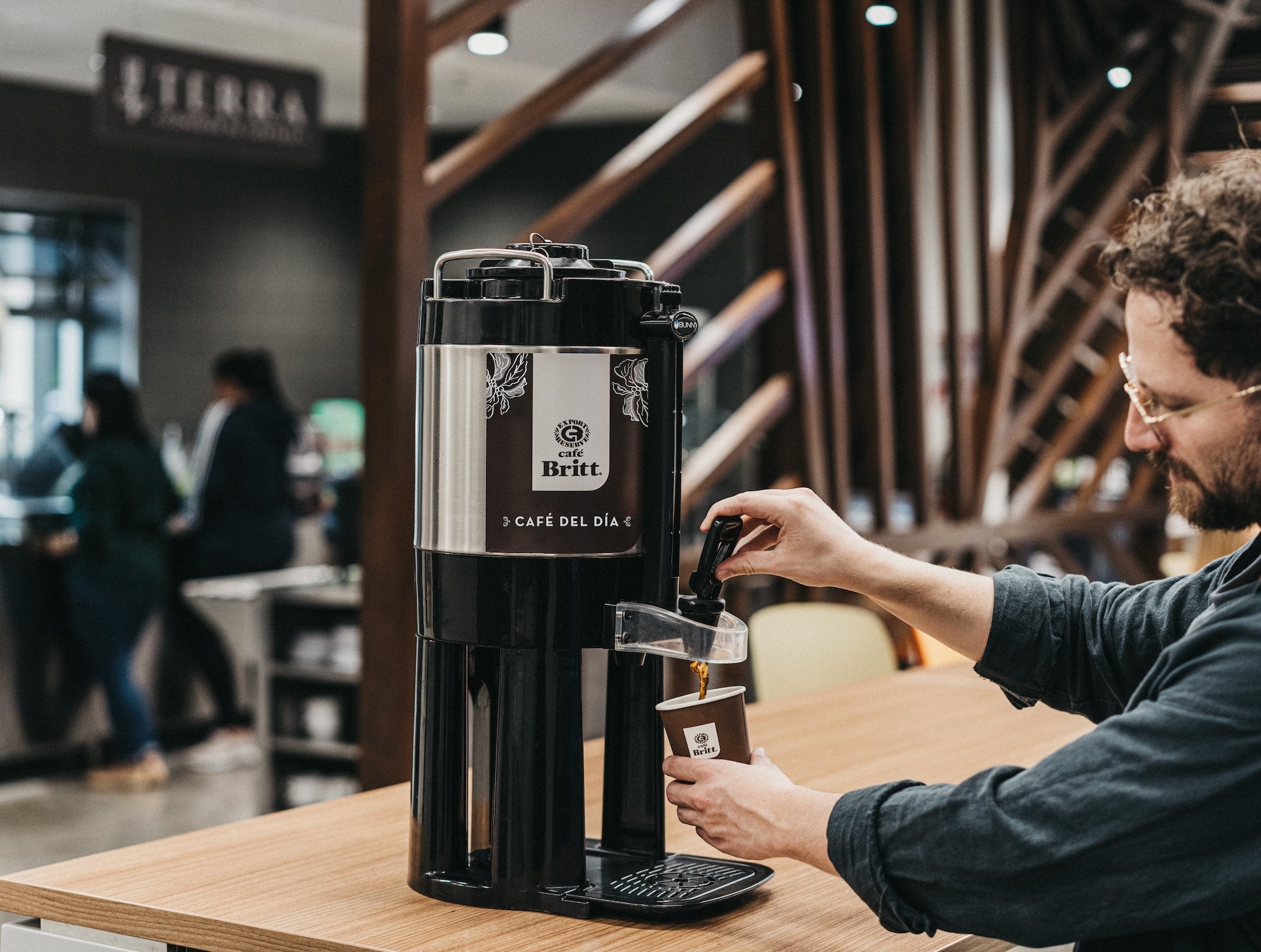Person serving from a Café Britt commercial coffee machine.