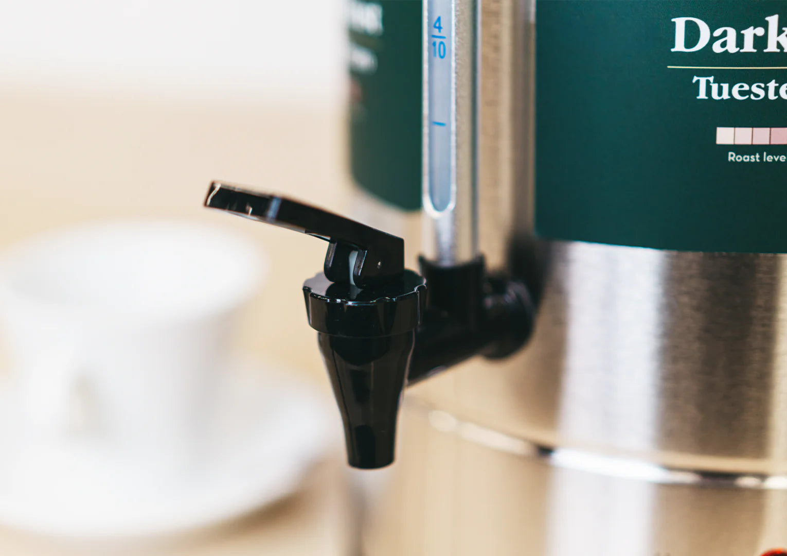 Coffee machine with a green container labeled 'Dark Tuest' on a blurred background