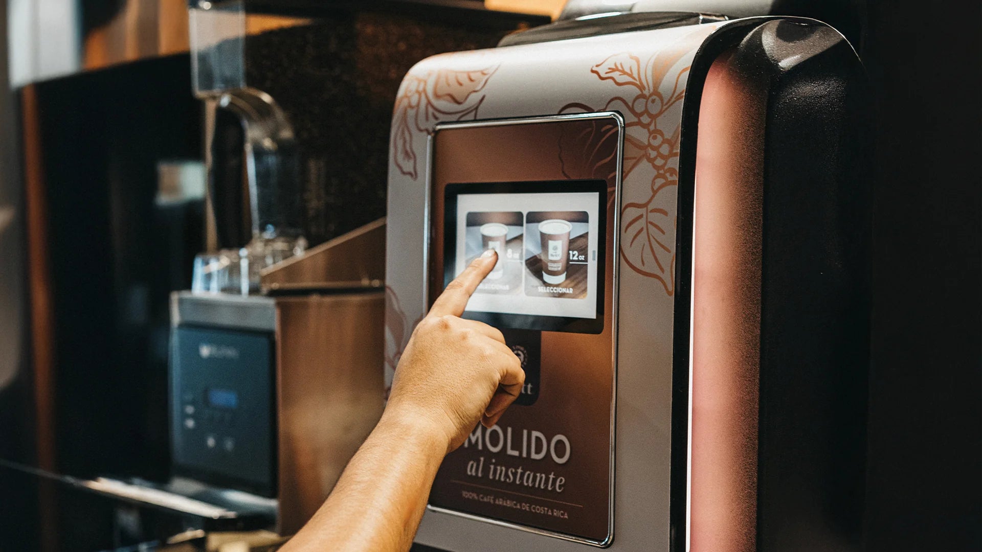 Hand interacting with a coffee machine's touch screen interface.