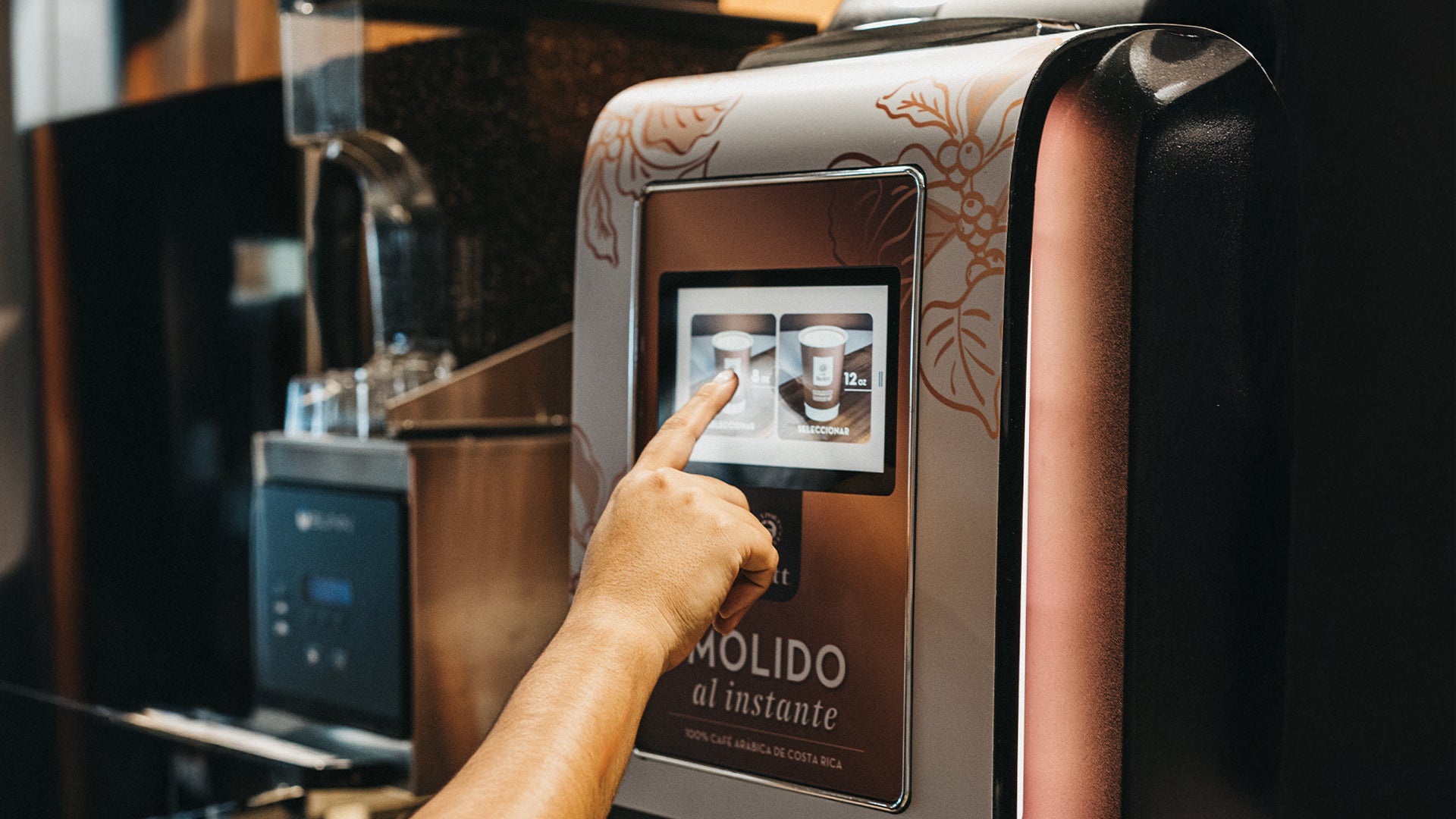 Person selecting Café Britt gourmet Costa Rican coffee on a Krea Touch commercial coffee machine touchscreen.