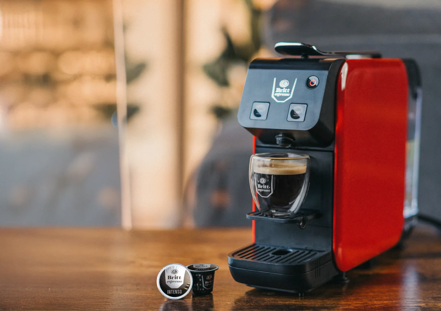 Kubo Red and black espresso machine on a wooden surface with blurred background