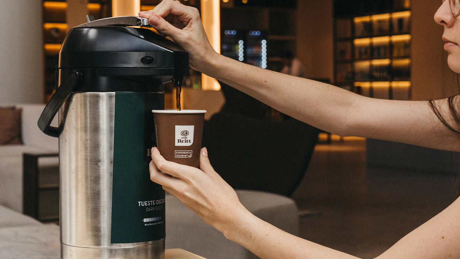 Person pouring Café Britt gourmet Costa Rican coffee into a cup in a hotel lobby.